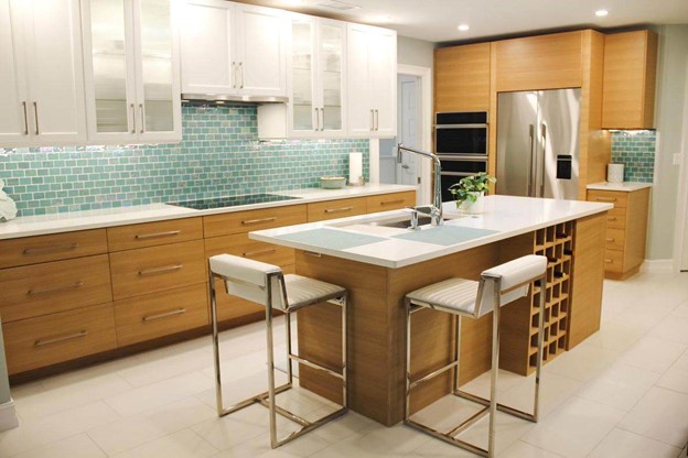 A kitchen with seafoam green tile backsplash, white cabinets and white countertops